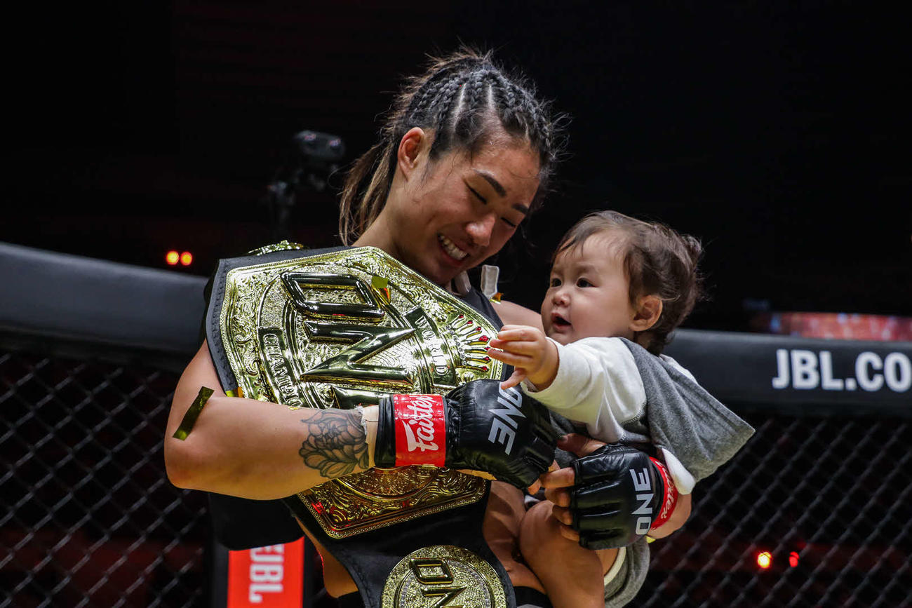 王座を防衛したアンジェラ（左）は娘を抱えて笑顔（C） ONE Championship