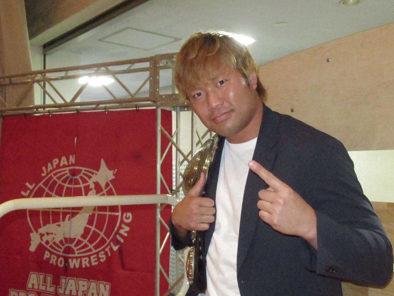 3冠ヘビー級王座ベルトを肩にかけ、ポーズを取る全日本プロレスの宮原（撮影・勝部晃多）