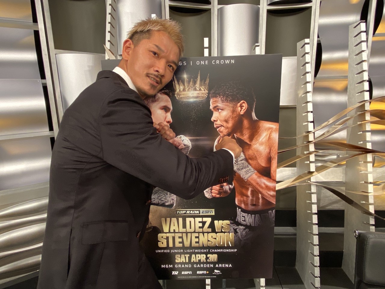 WBC、WBO世界スーパーフェザー級王者となったスティーブンソンの写真に拳を向けるIBF世界同級王者尾川（WOWOW提供）