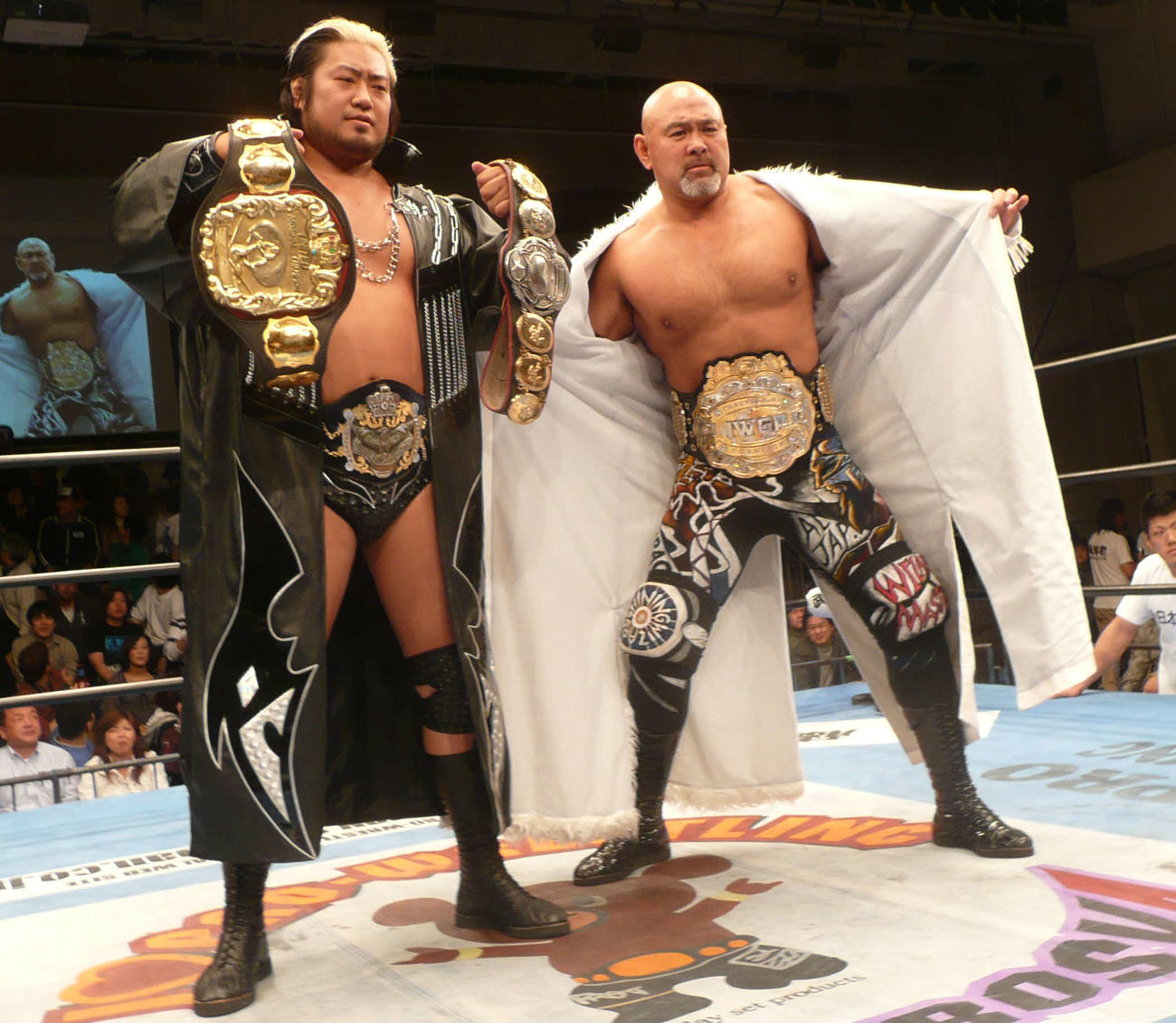 全日本後楽園大会　IWGPベルトを巻いた武藤敬司（右）と3冠ベルトを披露する諏訪魔。