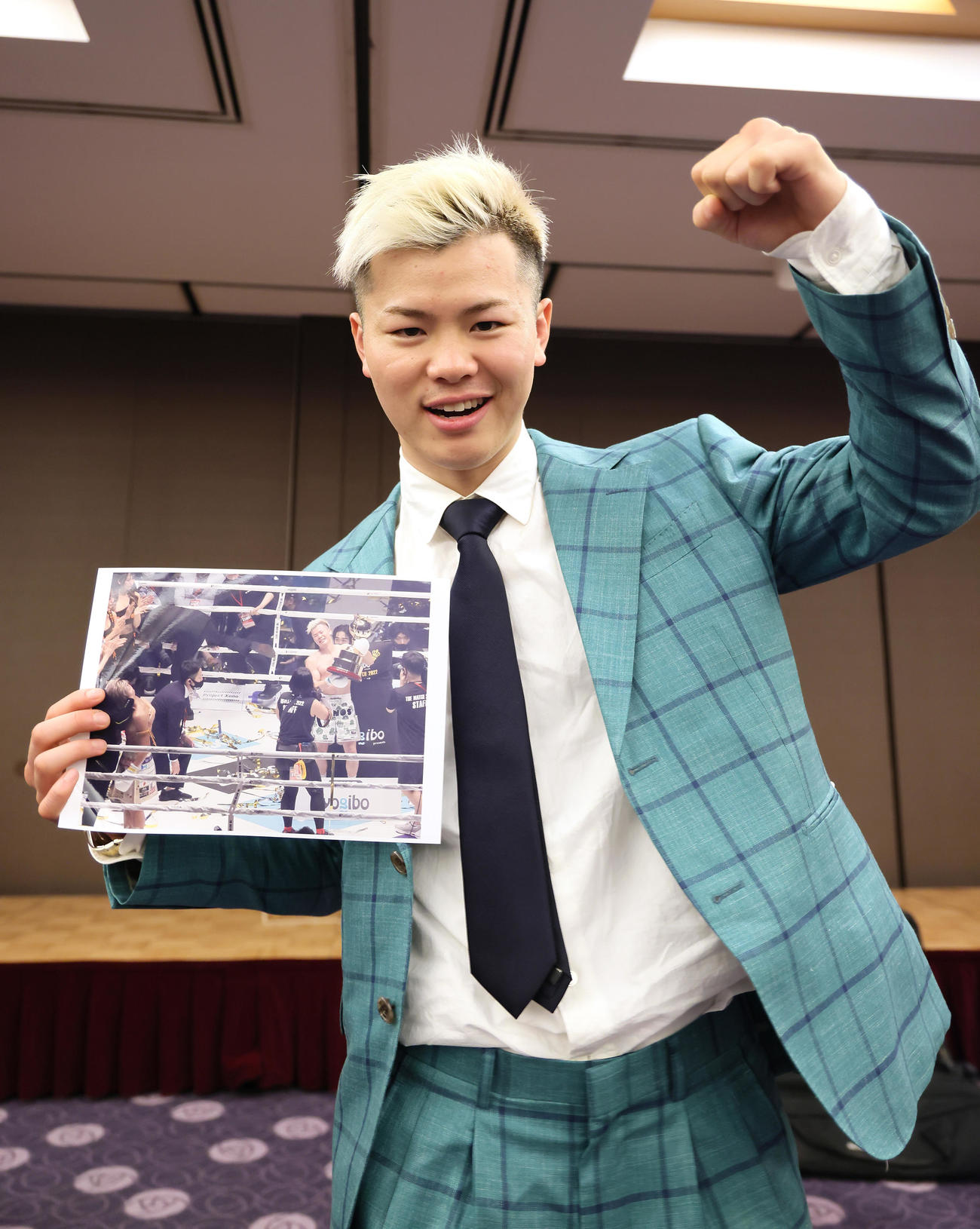 試合の写真を手にガッツポーズする那須川（撮影・足立雅史）