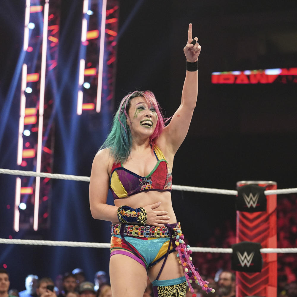 天井につるされたブリーフケースを指さすアスカ（C）2022 WWE, Inc. All Rights Reserved.