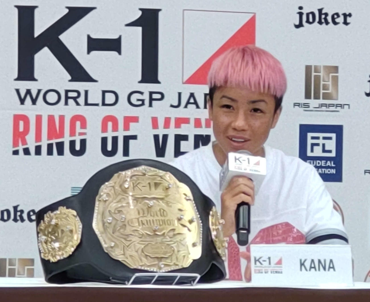 ベルトを横に笑顔で会見するK－1女子フライ級王者KANA（撮影・吉池彰）