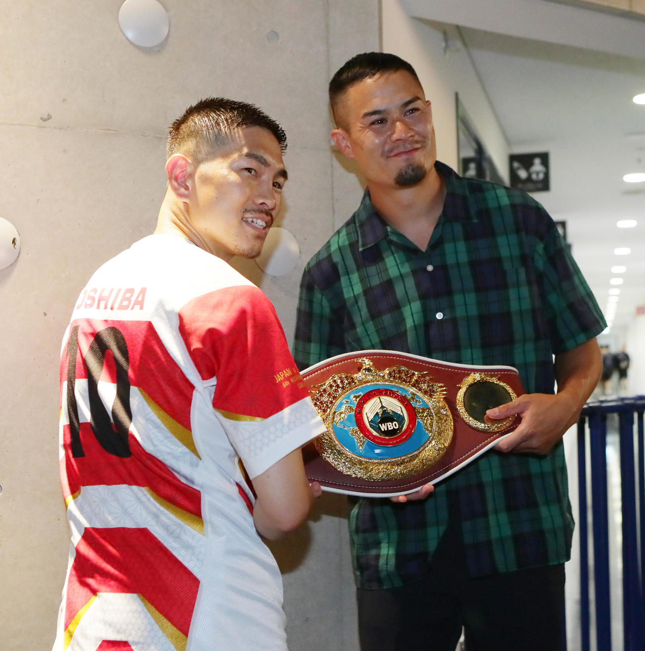 5度目の防衛に成功した井岡（左）はラグビー田村からユニホームをプレゼントされ笑顔を見せる（撮影・足立雅史）