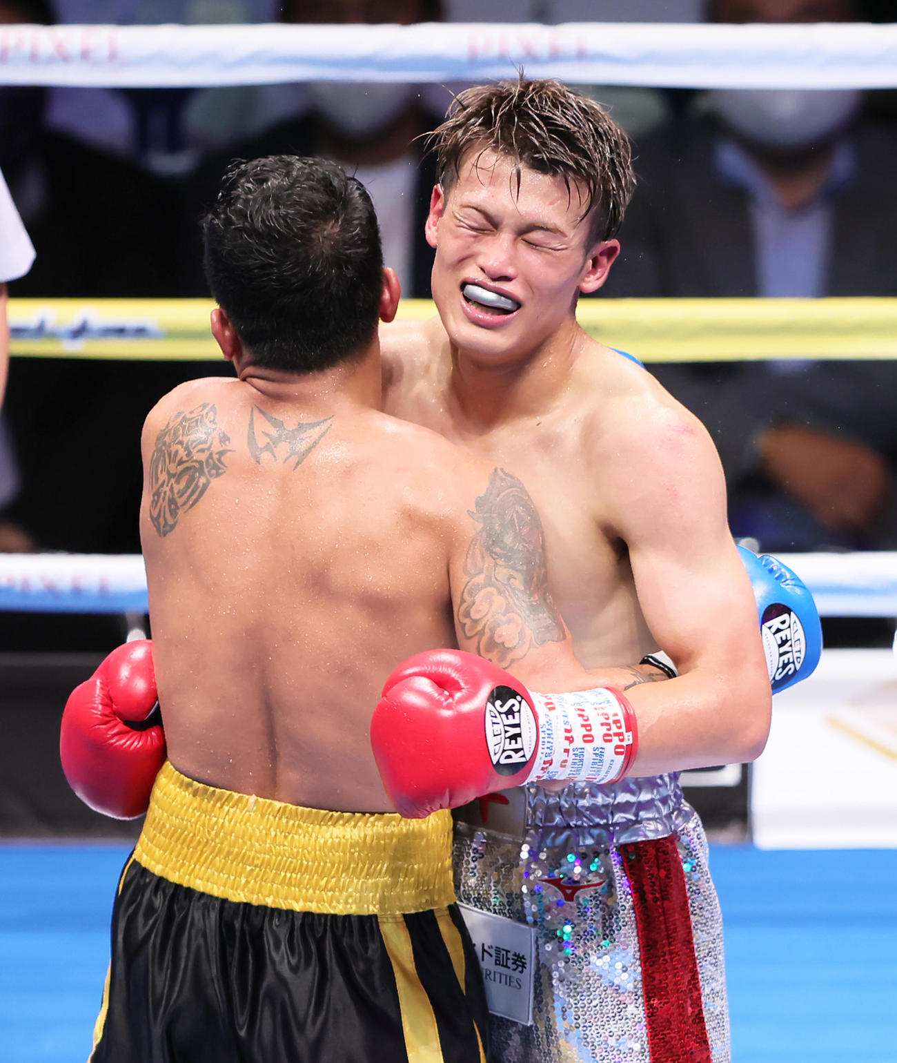 フェザー級8回戦　試合を終え、抱き合い健闘をたたえ合う堤（右）とジョン・ジェミノ（撮影・足立雅史）