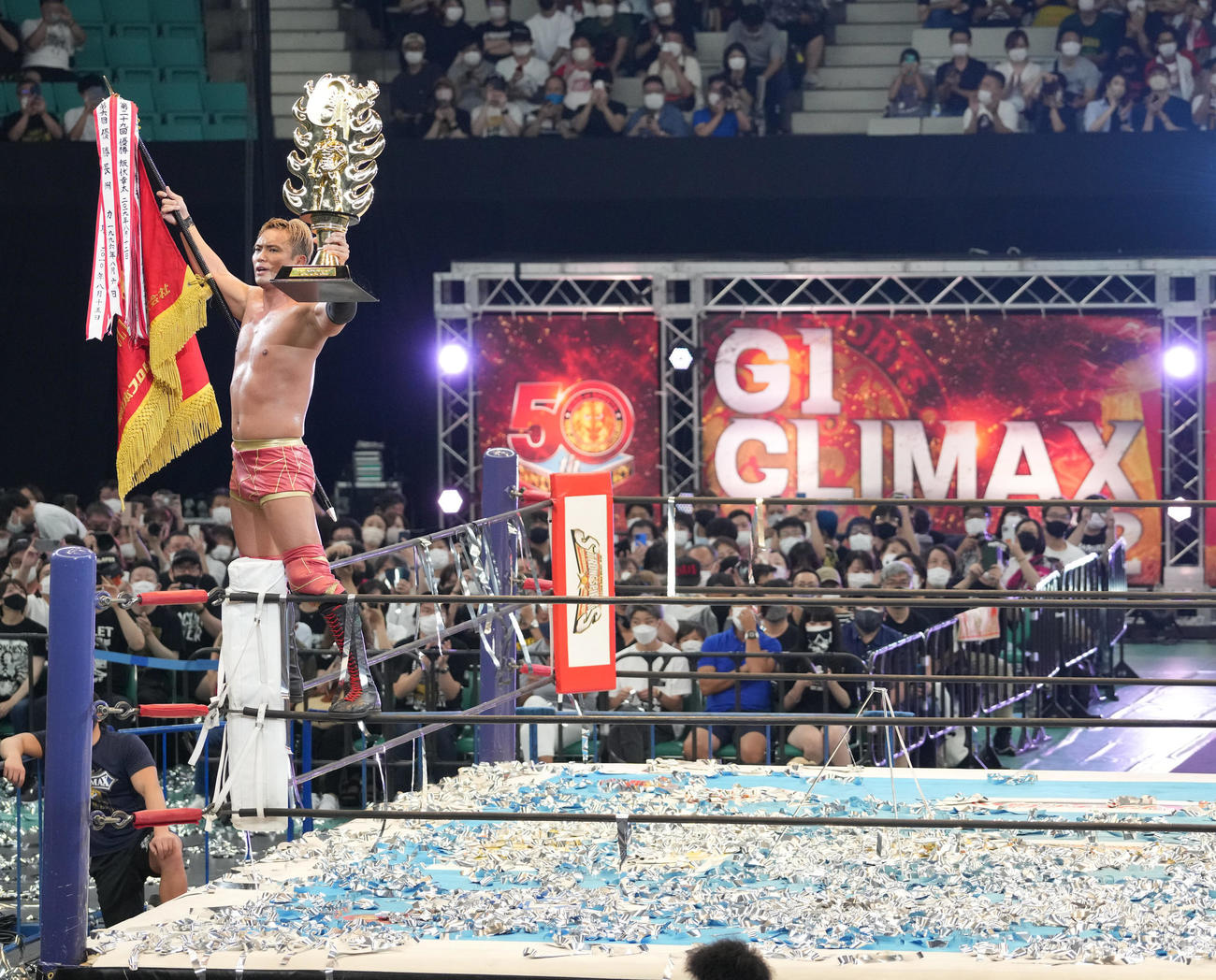 「G1クライマックス32」ファイナルトーナメント決勝戦、オカダ・カズチカ対ウィル・オスプレイ　G1を制しコーナートップでトロフィーと優勝旗を掲げるオカダ・カズチカ（撮影・小沢裕）