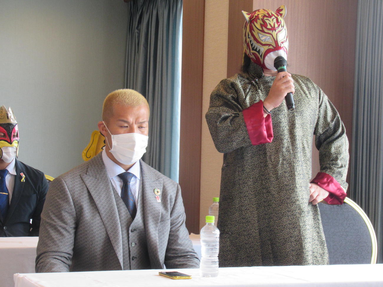 「天王山2022」記者会見で、マイクを握るタイガースマスク。左は社長兼レスラーのゼウス（撮影・益田一弘）