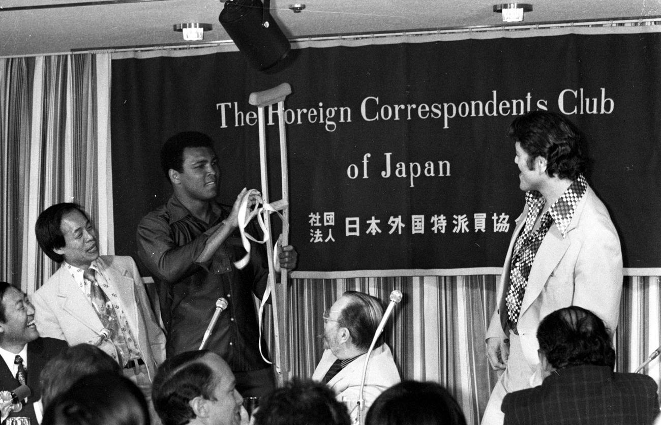 76年6月、異種格闘技戦のため来日したムハマド・アリさん（左から3人目）は外国人記者クラブでの会見でアントニオ猪木さん（右）から松葉づえをプレゼントされる