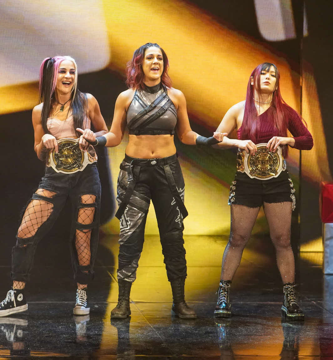 WWE女子タッグ王座ベルトを巻き、ベイリー（中央）と入場するイヨ・スカイ（右端）とダコタ・カイ（C）2022 WWE, Inc. All Rights Reserved.