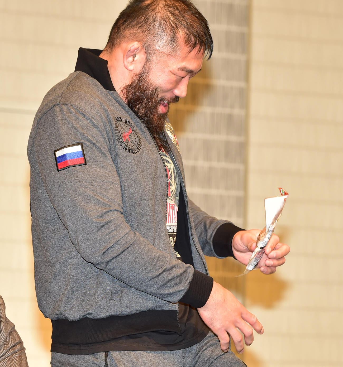前日会見、ほかの対戦カードの選手が挑発で出してきたサラダチキンを名乗り出て受け取りうれしそうにするサトシ・イシイ（撮影・清水貴仁）