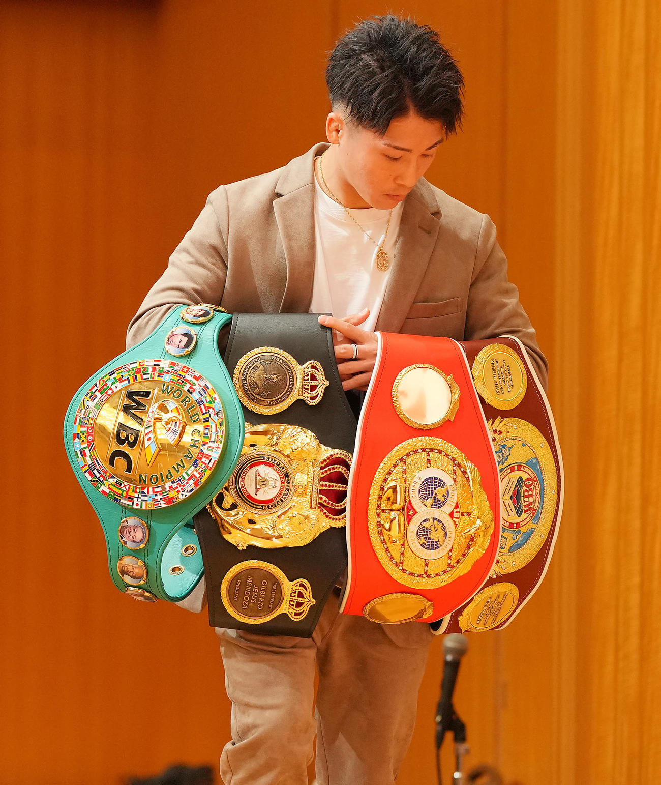 会見を終え4本のベルトを抱え壇上に上がる井上尚（撮影・垰建太）
