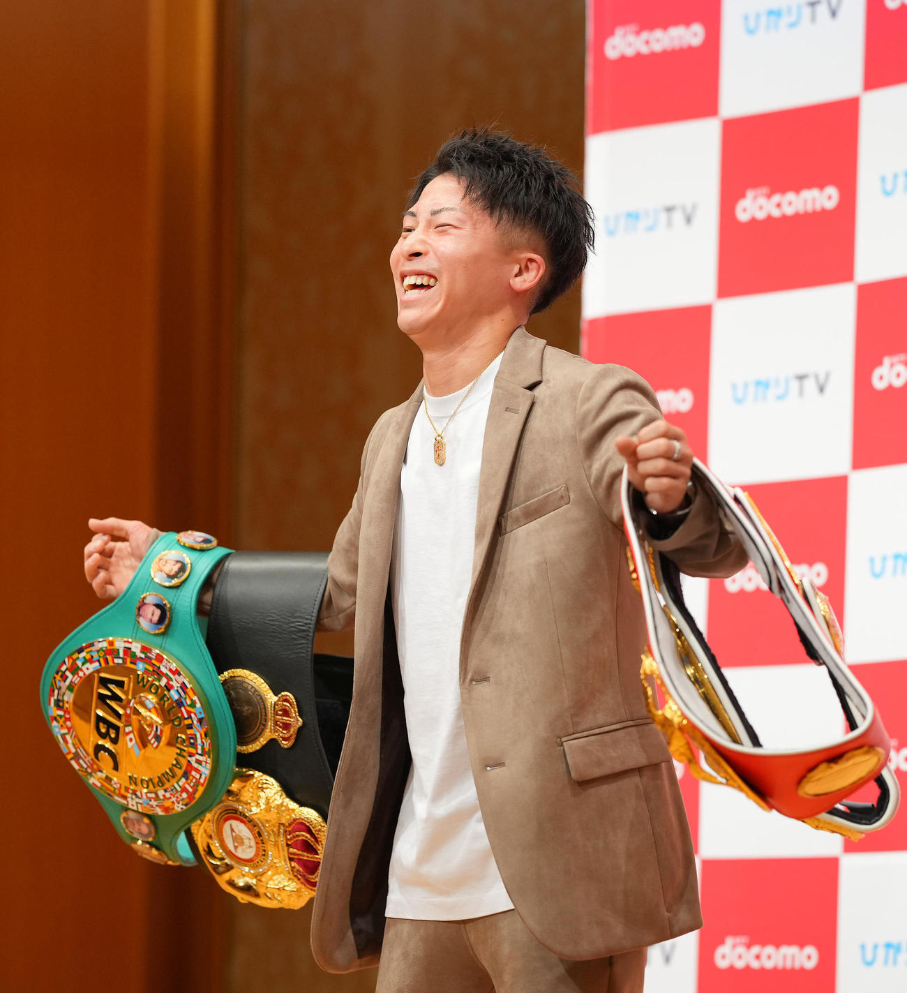 会見を終え報道陣のリクエストに応え4本のベルトを腕にぶら下げるも重みに耐えきれず苦笑いの井上尚（撮影・垰建太）
