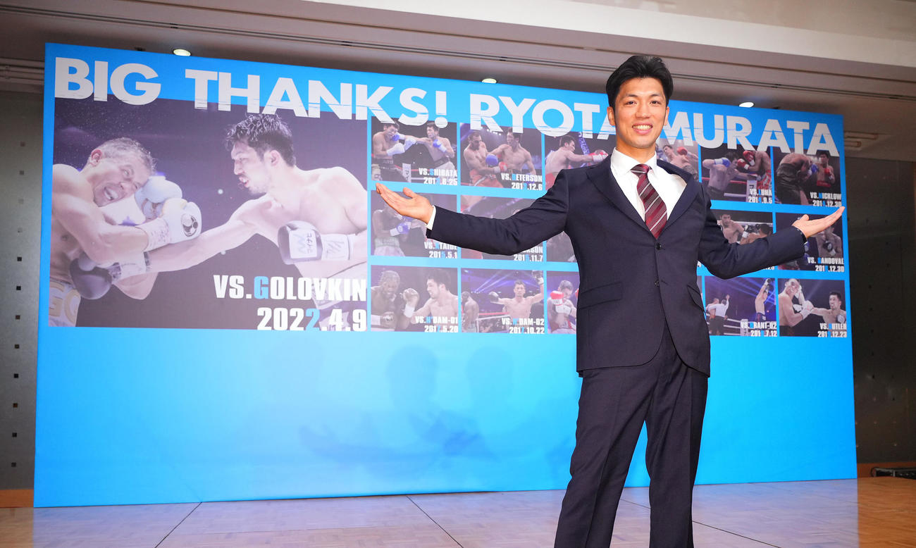 引退会見を終えプロデビュー戦からの写真が貼られたボードを手に写真に納まる村田（撮影・垰建太）