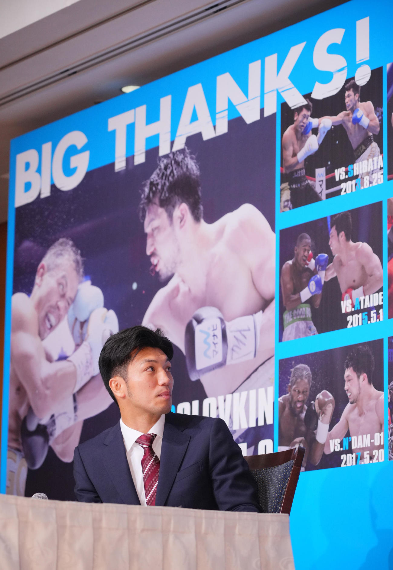 引退会見でに置かれたプロデビュー戦からの写真が貼られたボードを見つめる村田（撮影・垰建太）
