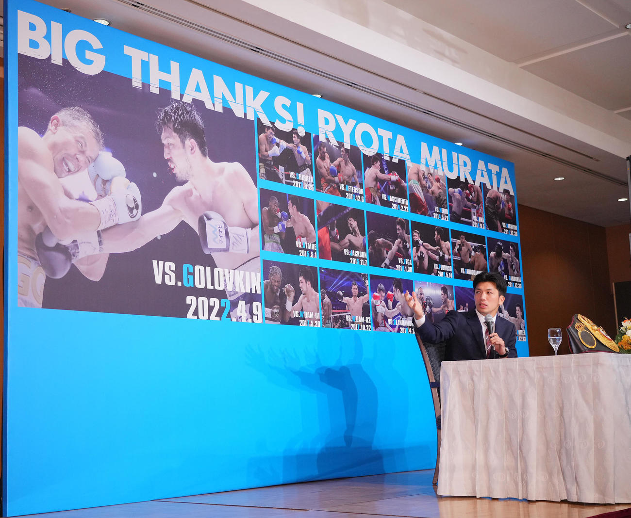引退会見に置かれたプロデビュー戦からの写真が貼られたボードを見つめながら思い出を語る村田（撮影・垰建太）