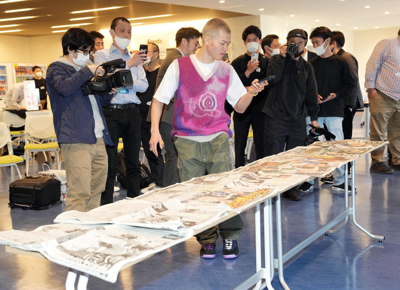 ボクシング初戦初勝利後の一夜明け会見で自身が掲載されたスポーツ紙をスマホで撮影する那須川（撮影・狩俣裕三）