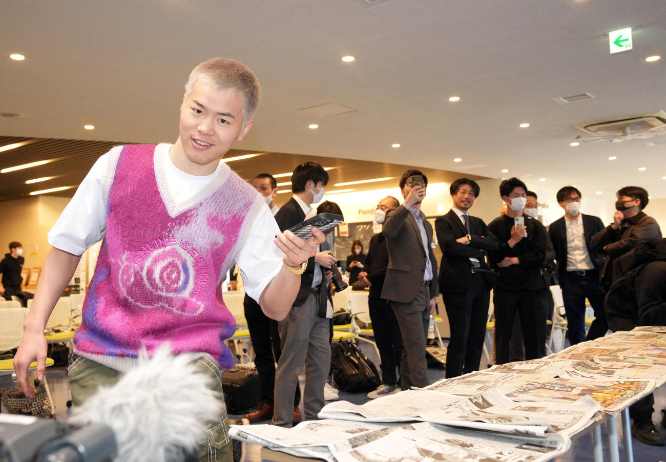 ボクシング初戦初勝利後の一夜明け会見で自身が掲載されたスポーツ紙をスマホで撮影する那須川（撮影・狩俣裕三）