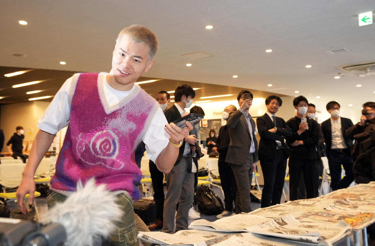 ボクシング初戦初勝利後の一夜明け会見で自身が掲載されたスポーツ紙をスマホで撮影する那須川（撮影・狩俣裕三）