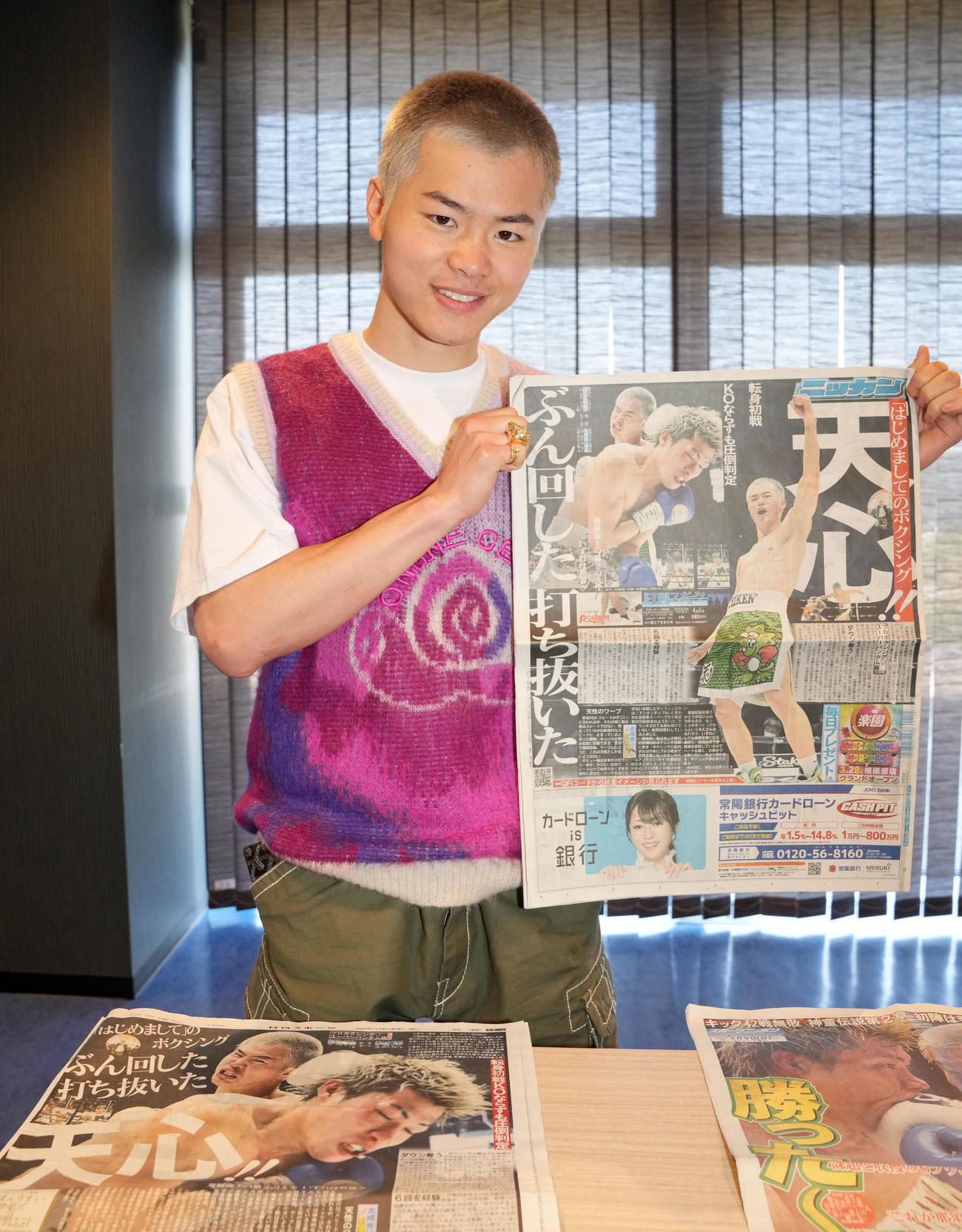 ボクシング初戦初勝利後の一夜明け会見で、本紙を手に笑顔を見せる那須川（撮影・狩俣裕三）