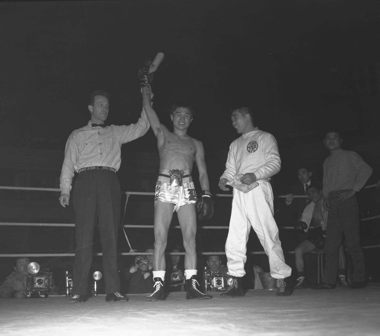 全日本フライ級選手権　米倉健治（判定）福本篤　空位となった王座を同門福本篤と争い奪取した米倉健治（中央）、左は米国人レフェリーのニッキー・ポップ（1959年1月4日撮影）