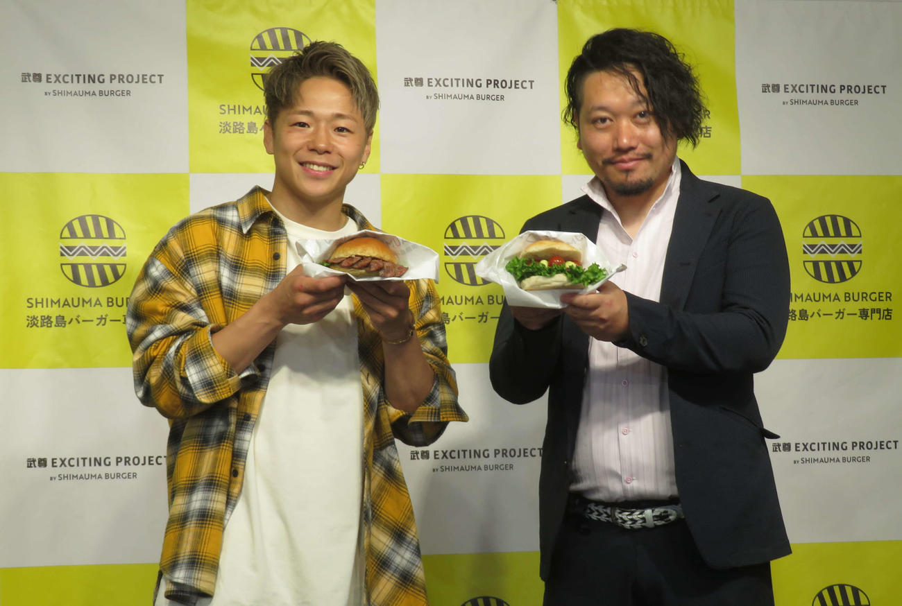 SHIMAUMA BURGERの町口匡貴社長（右）とコラボバーガーを手に笑顔をみせる武尊