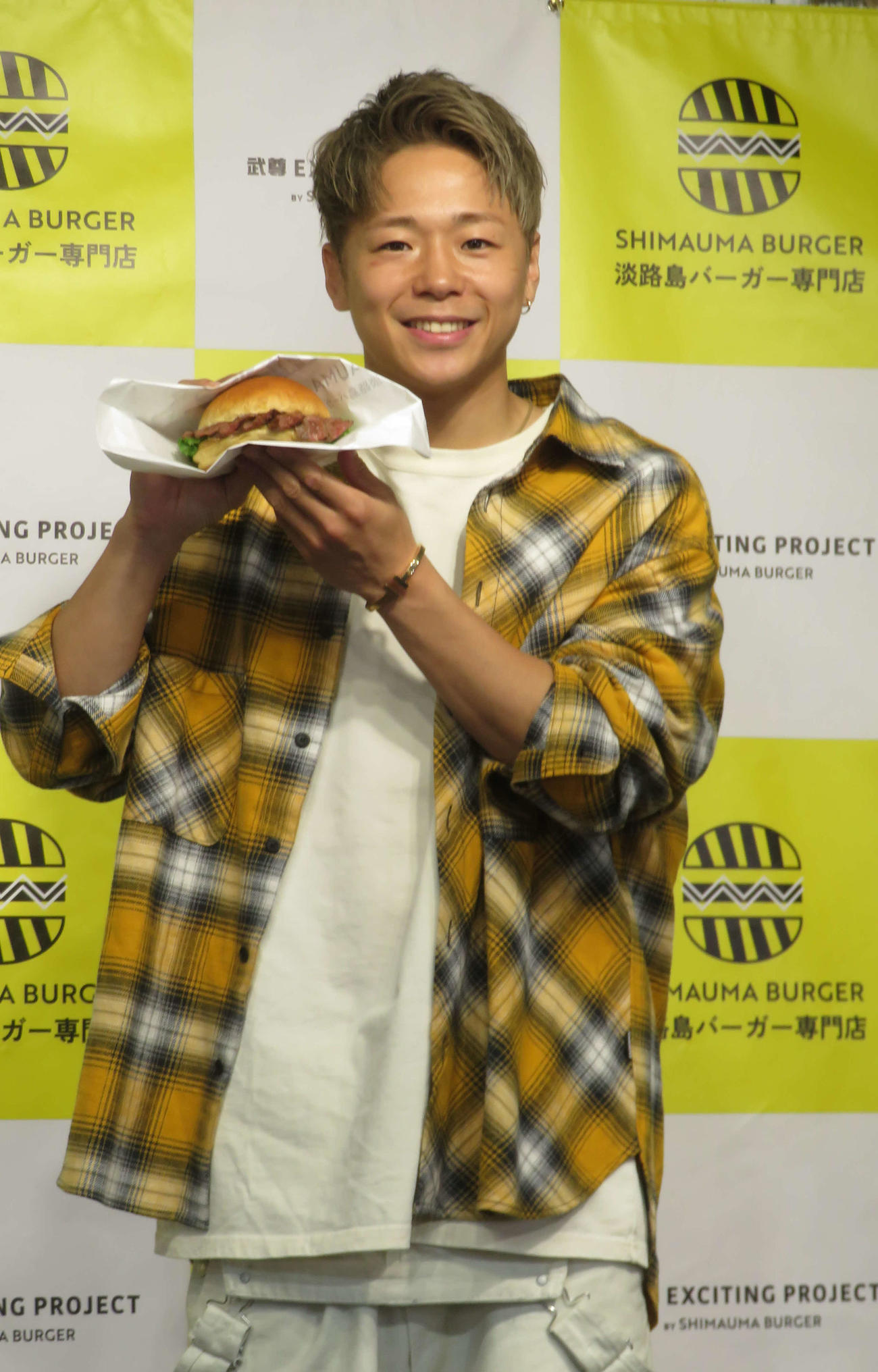 SHIMAUMA BURGERとコラボしたグルメバーガーを手にする武尊