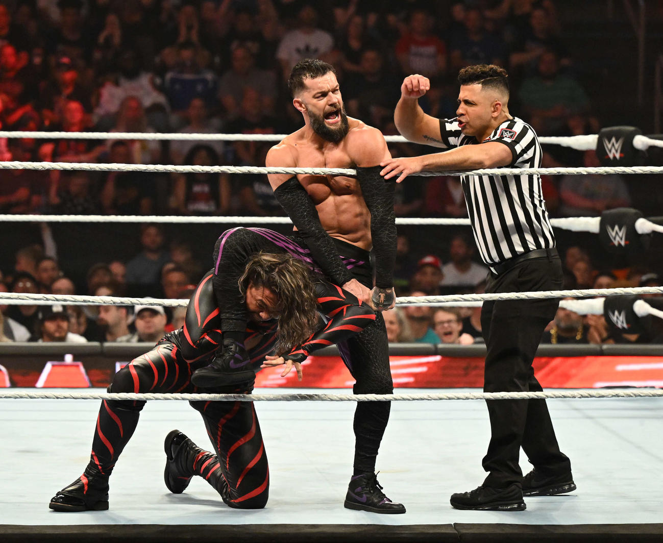 フィン・ベイラー（中央）にロープ際で攻められる中邑真輔（左端）コピーライト2023 WWE, Inc. All Rights Reserved.
