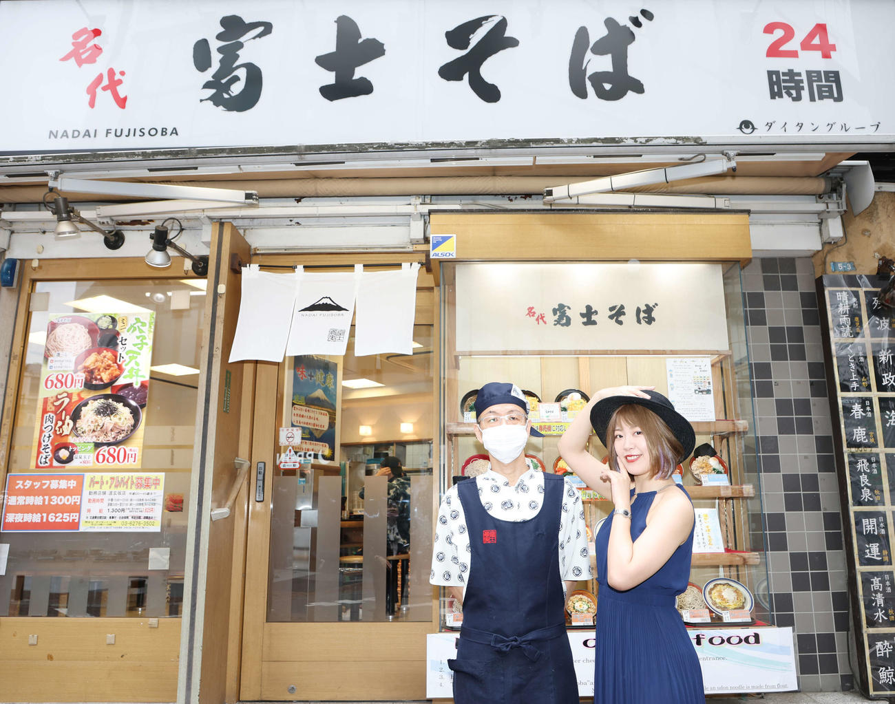 富士そばを訪れ、貴婦人ポーズを取り、店長と記念写真に納まる桜井まい（撮影・宮地輝）