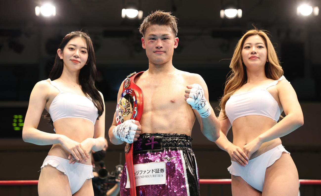 東洋太平洋フェザー級王者に輝きラウンドガールとポーズを決める堤（撮影・中島郁夫）