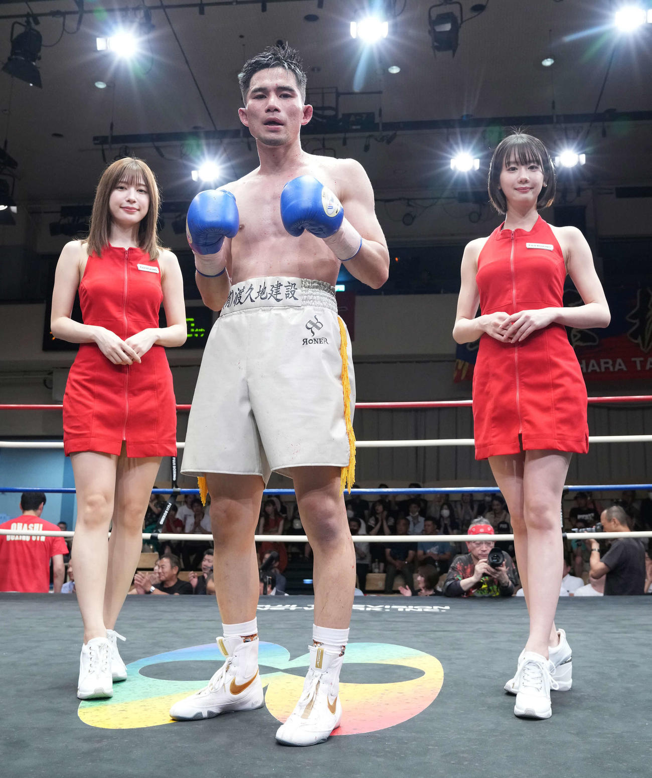 判定勝ちを収めファイティングポーズを披露するニューサンダー照屋（中央）。左はラウンドガールの雪平莉左、右は新唯（撮影・小沢裕）