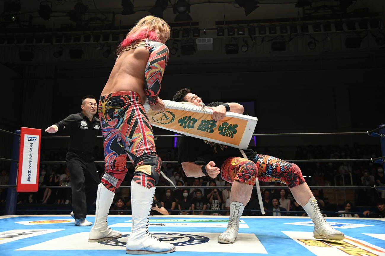 新日本のスポンサーの吉野家が入ったコーナークッションを手にする棚橋弘至ともみ合う矢野通（新日本プロレス提供）