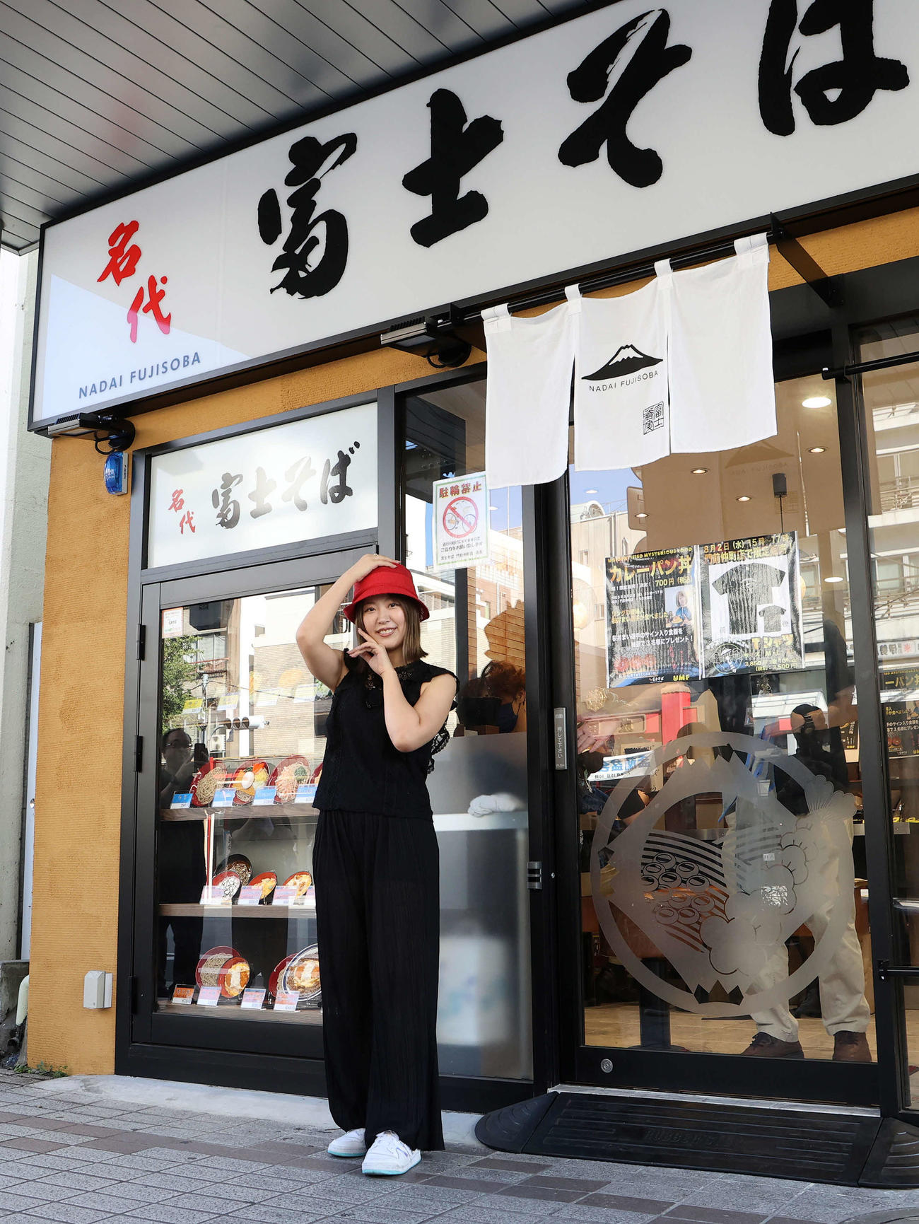 富士そば店舗前でポーズする桜井まい（撮影・鈴木正人）