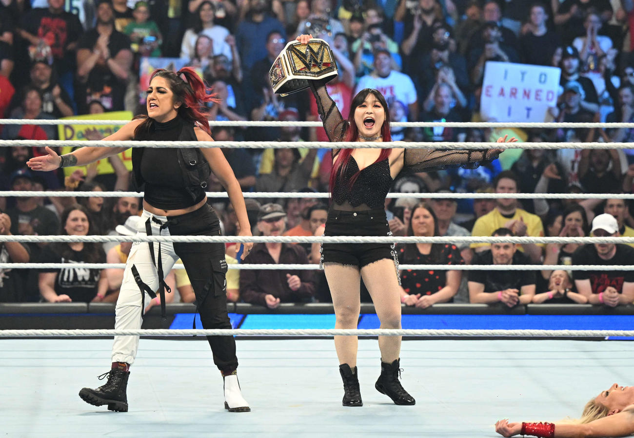 リングの中央でWWE女子王座ベルトを掲げる王者イヨ・スカイ（中央）。左端はベイリー（C）2023 WWE, Inc. All Rights Reserved.