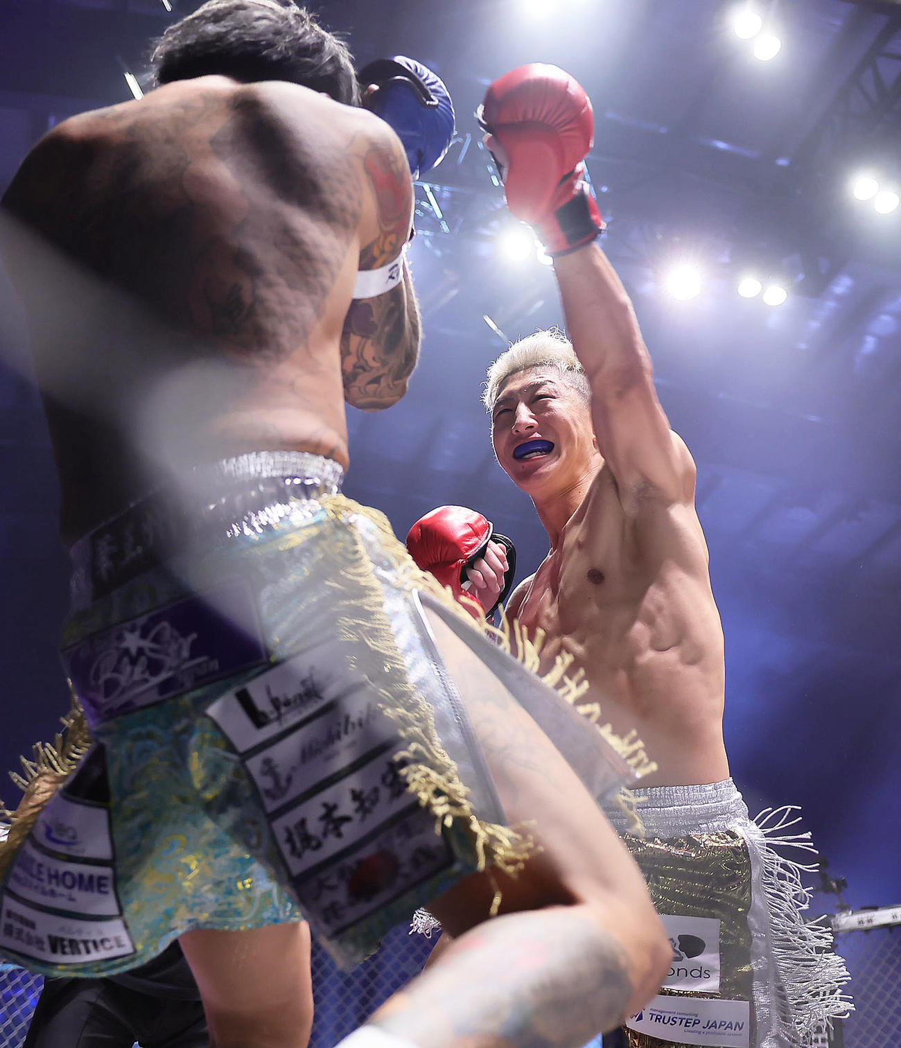 竜毅（左）に笑みを浮かべながらパンチを見舞う冨沢（撮影・足立雅史）