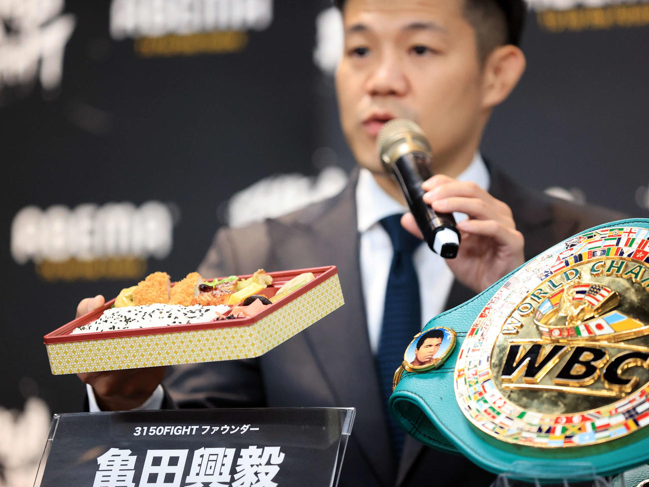 「3150FIGHT vol．7」W世界タイトルマッチ会見で幕の内弁当を手に試合の趣旨を説明する亀田興毅ファウンダー（撮影・浅見桂子）