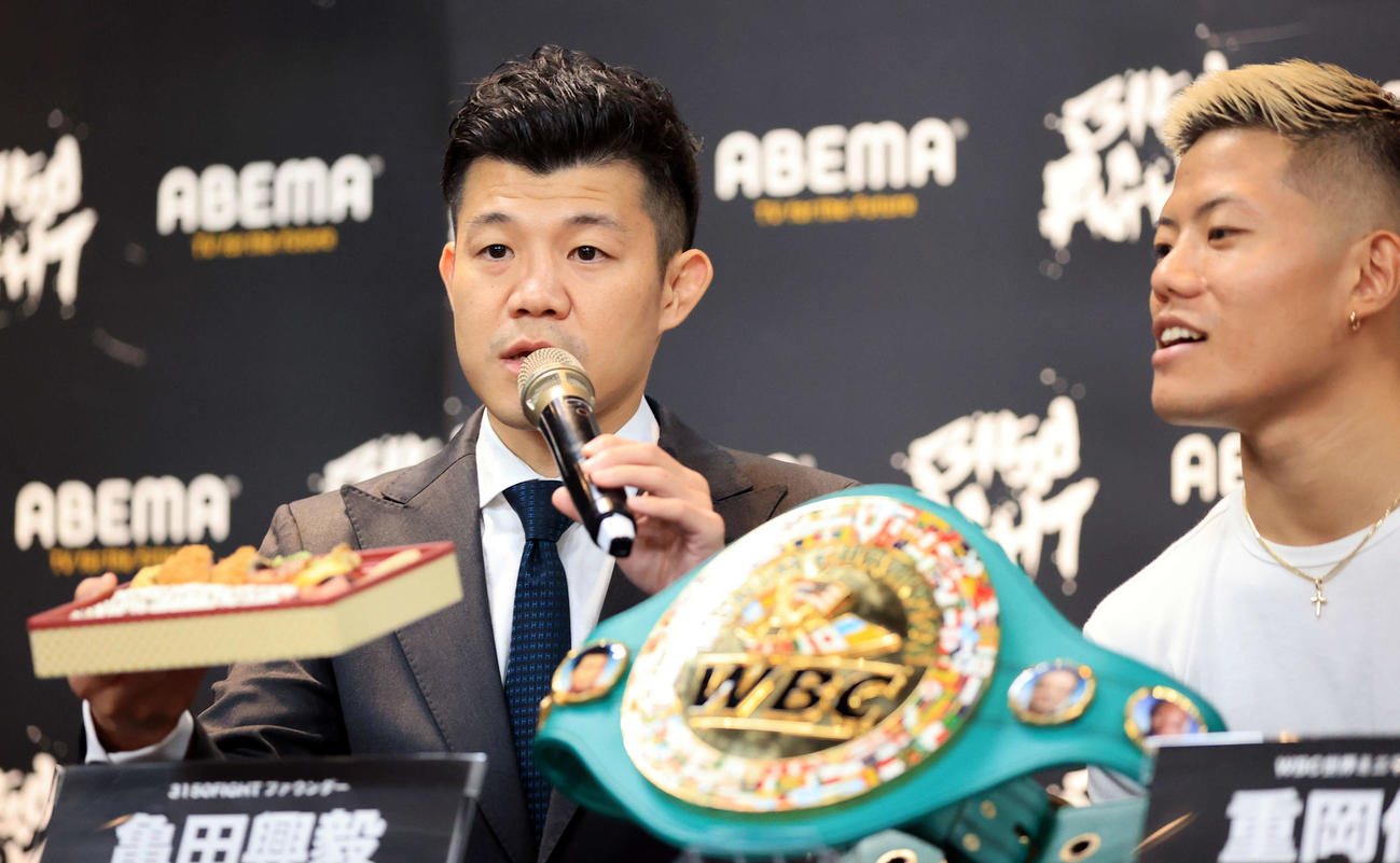 「3150FIGHT vol．7」ダブル世界タイトルマッチ会見で幕の内弁当を手に試合の趣旨を説明する亀田興毅ファウンダー（左）。右は重岡優大（撮影・浅見桂子）