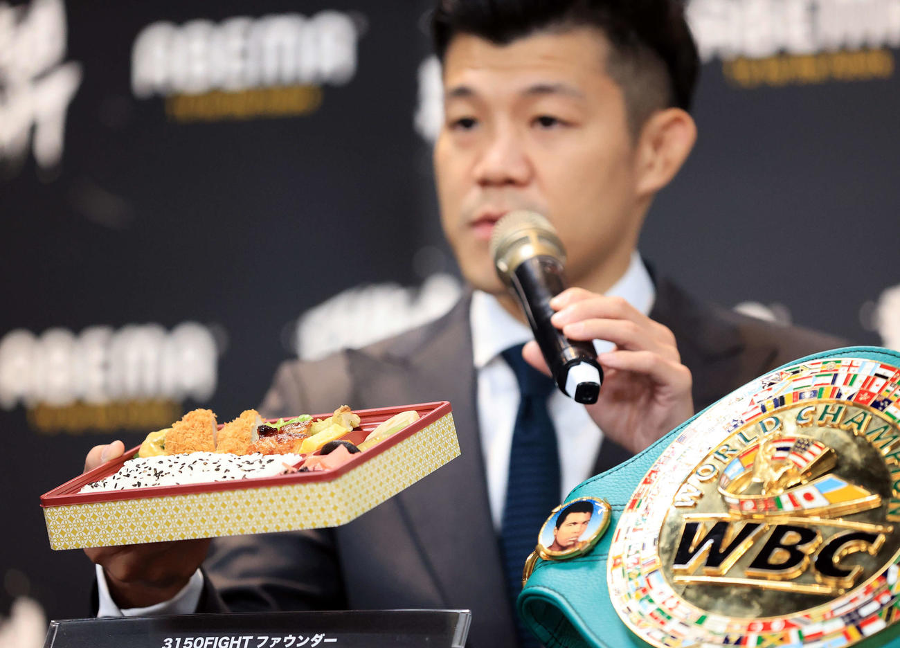 「3150FIGHT vol．7」ダブル世界タイトルマッチ会見で幕の内弁当を手に試合の趣旨を説明する亀田興毅ファウンダー（撮影・浅見桂子）