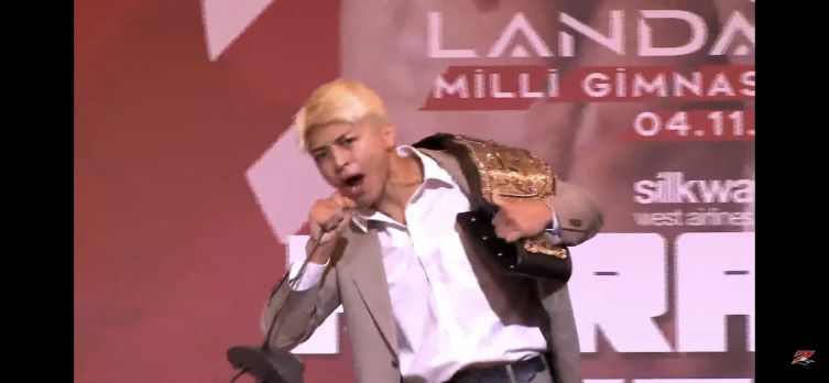 RIZINアゼルバイジャン大会カード発表で、ヴガール・ケラモフのベルトを強奪する鈴木千裕（RIZINのYouTubeから）