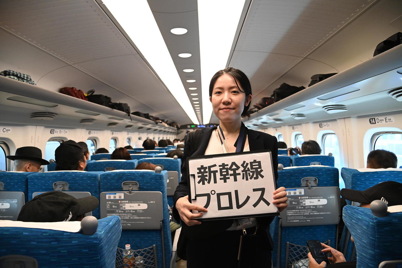 新幹線プロレスと書かれた紙を持ち、案内するスタッフ（DDTプロレス提供）
