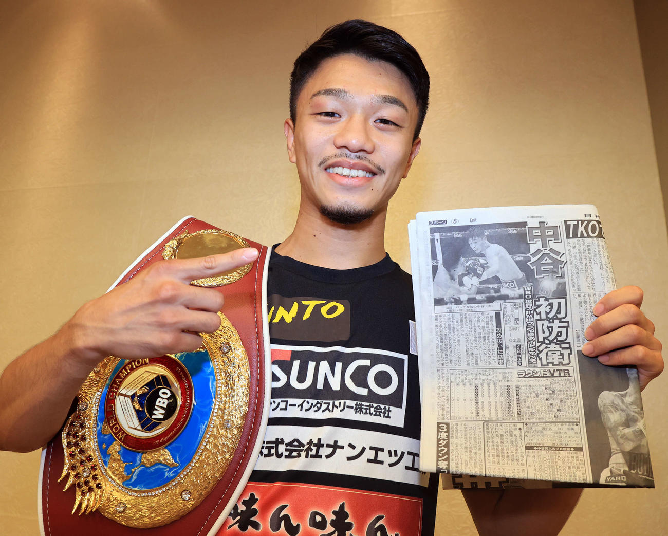初防衛戦から一夜明けた会見で、本紙を手に笑顔でポーズをとる中谷潤人（撮影・浅見桂子）