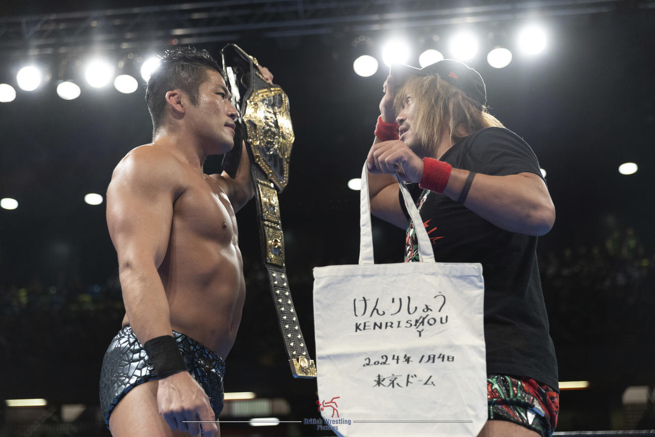 IWGP世界ヘビー級のベルトをアピールするSANADA（左）の前に、お手製のIWGP世界ヘビー級選手権の挑戦権「けんりしょう」のトートバックを手にする内藤哲也（新日本プロレス提供）