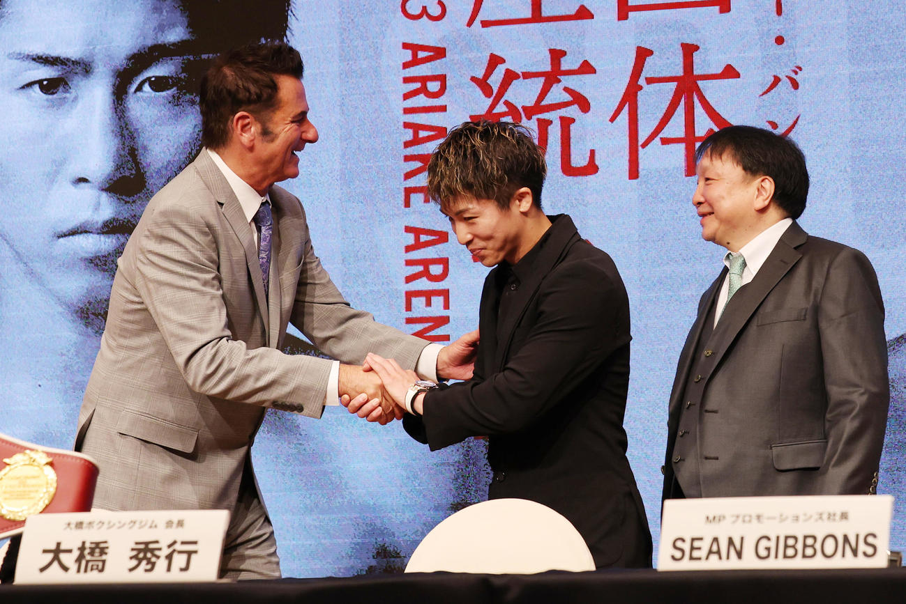 マーロン・タパレスとのWBA・WBC・IBF・WBO世界スーパーバンタム級王座統一戦の発表会見で、タパレスのプロモーター、MPプロモーションズのギボンズ社長（左）と握手する井上尚弥。右は大橋ジムの大橋会長（撮影・野上伸悟）