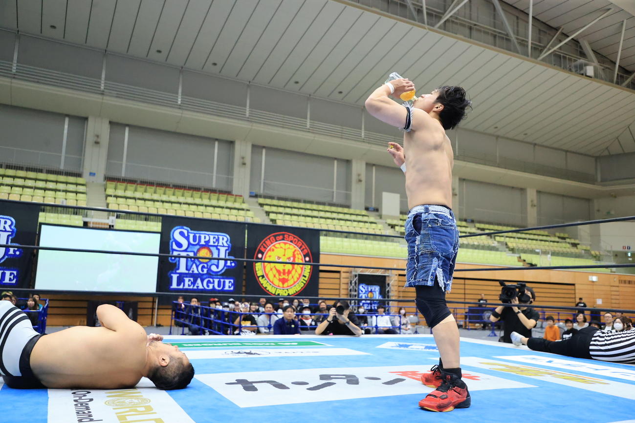 金丸義信（左）のウイスキーの瓶を強奪し、ラッパ飲みするYOH（新日本プロレス提供）