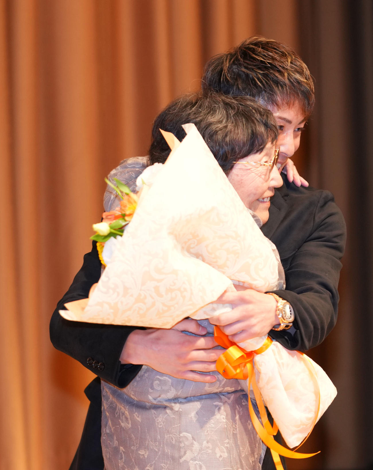壇上で大橋会長の母・ヒサ子さん（手前）を抱き締める井上尚（撮影・横山健太）