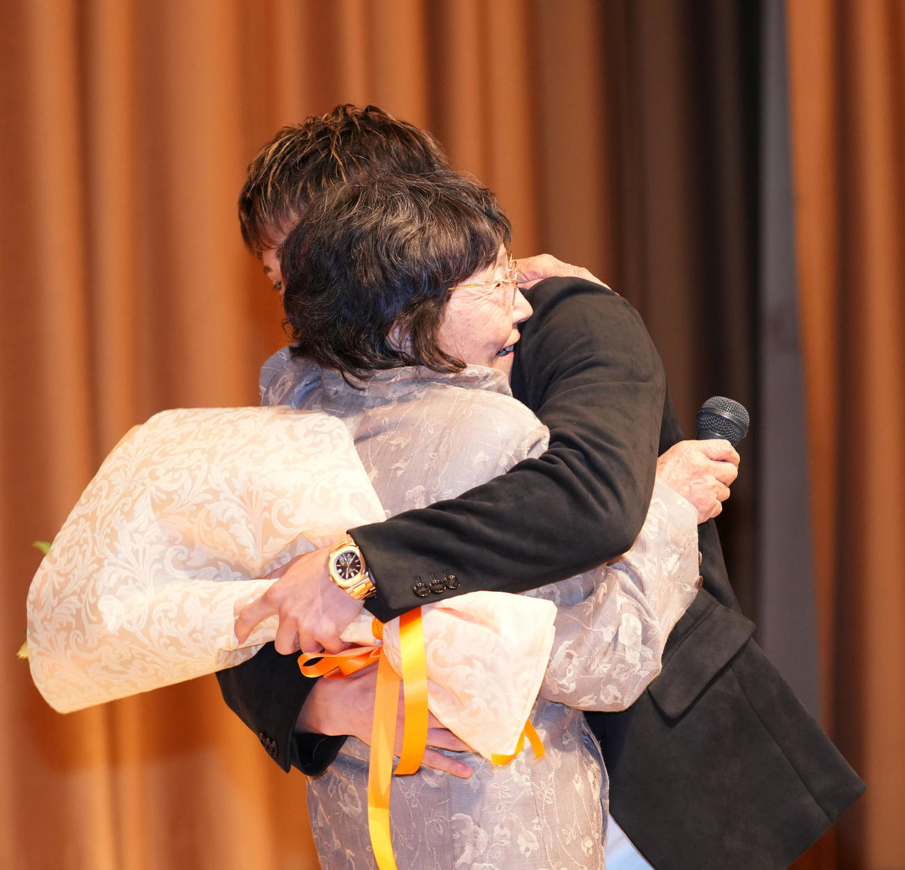 壇上で大橋会長の母・ヒサ子さん（手前）を抱き締める井上尚（撮影・横山健太）
