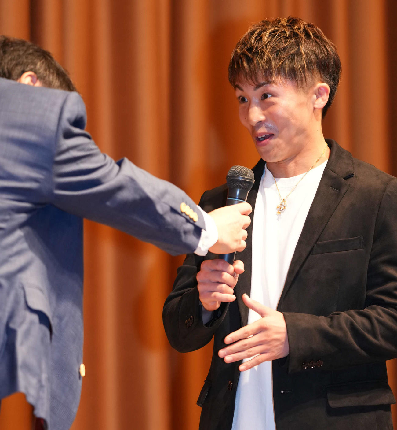 大橋会長（左）からマイクを渡され驚いた表情を見せる井上尚（撮影・横山健太）