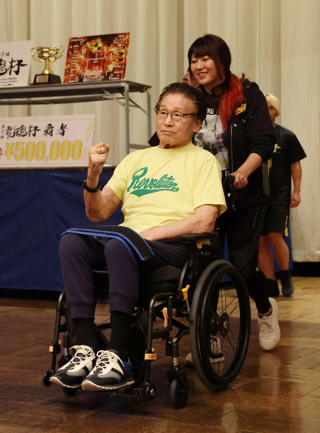 娘で天龍プロジェクト代表の嶋田紋奈さんが押す車椅子でリングへ向かう天龍源一郎さん（撮影・丹羽敏通）