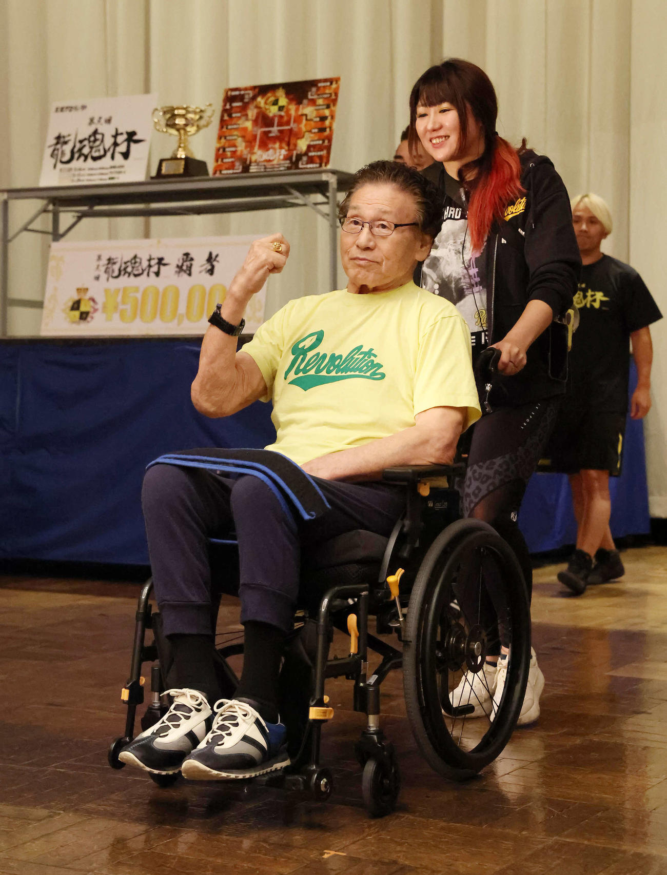 娘で天龍プロジェクト代表の嶋田紋奈さんが押す車椅子でリングへ向かう天龍源一郎さん（撮影・丹羽敏通）
