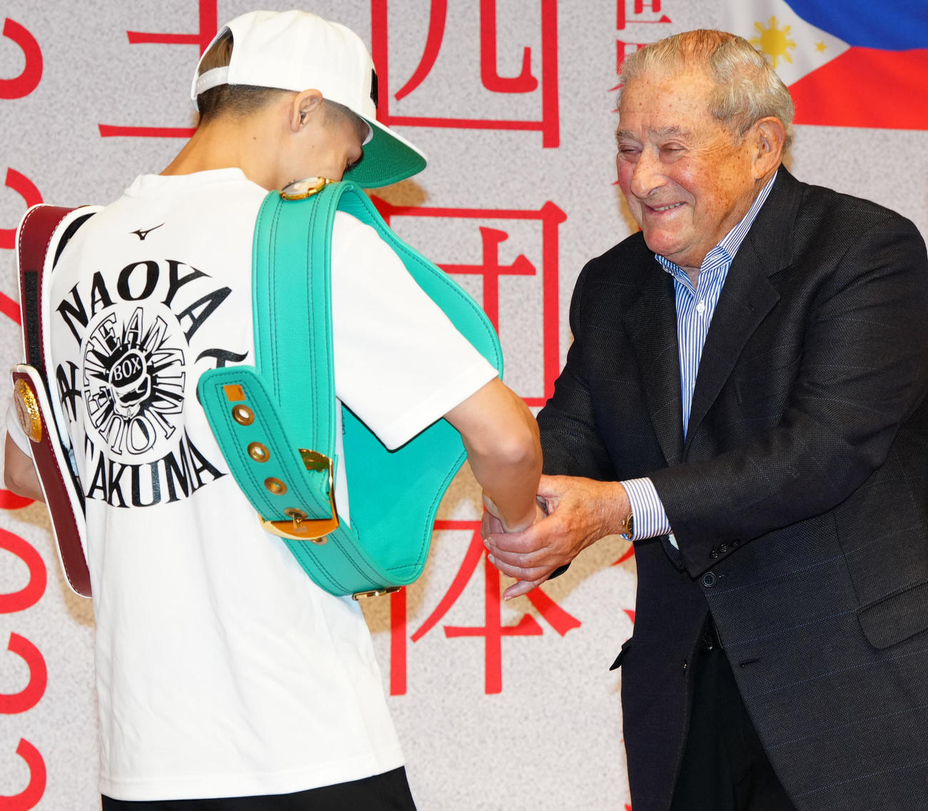 4団体王座統一戦前の会見でWBC、WBO世界スーパーバンタム級王者の井上尚（左）と握手を交わすアラム氏（撮影・江口和貴）