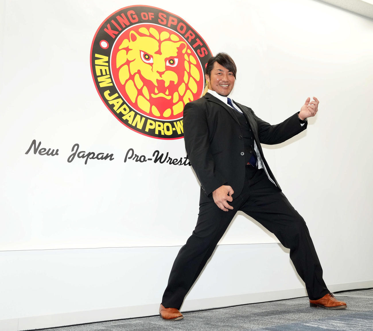 新日本プロレス新社長就任会見終了後、エンブレムの前でエアギターポーズを決める棚橋（撮影・たえ見朱実）